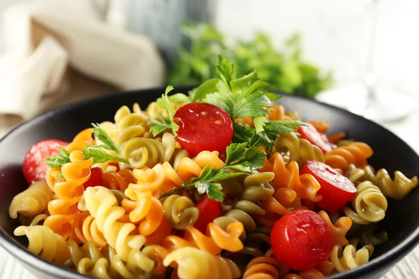 Delicioso plato de macarrones en tazón negro sobre mesa de madera gris servida — Foto de Stock