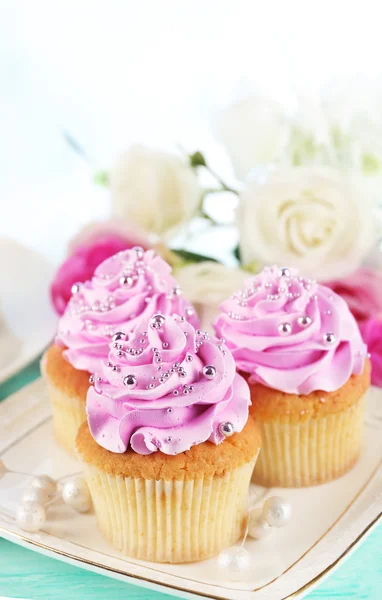 Leckere Cupcakes auf Teller, auf farbigem Holzhintergrund — Stockfoto