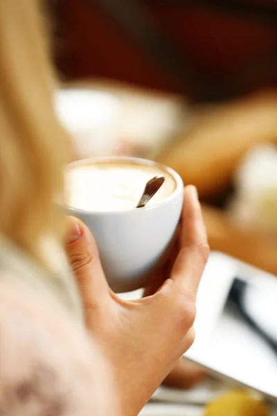 Mujer sosteniendo la taza de café en la cafetería — Foto de Stock