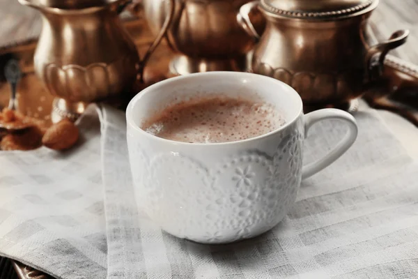 Чашка гарячого какао на бавовняній серветці проти срібного сервісу — стокове фото