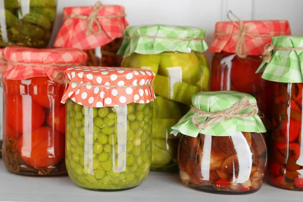 Jars with pickled vegetables and beans on wooden shelf — Stock Photo, Image