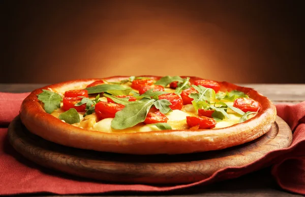 Pizza Margherita mit Rucola und Serviette auf braunem Hintergrund — Stockfoto
