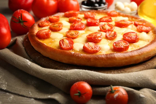 Pizza Margherita with vegetables and plunger on wooden table — Stock Photo, Image