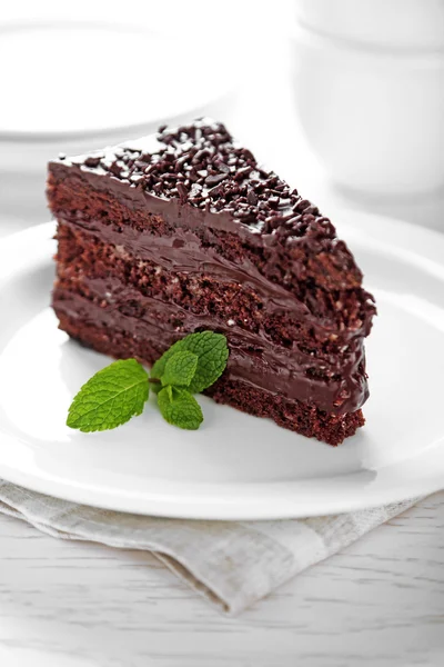 Chocolate cake met chocolade crème op plaat, op lichte achtergrond — Stockfoto