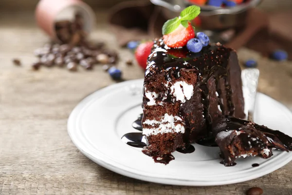 Κέικ σοκολάτας με κρέμα και φρέσκα μούρα στο πιάτο, σε ξύλινο φόντο — Φωτογραφία Αρχείου