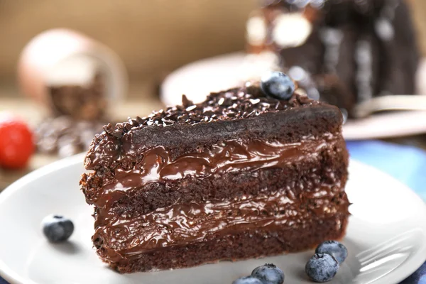 Schokoladenkuchen mit Schokoladencreme und frischen Blaubeeren auf Teller, auf Holzgrund — Stockfoto