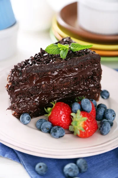 Torta al cioccolato con crema di cioccolato e bacche fresche su piatto, su fondo di legno — Foto Stock