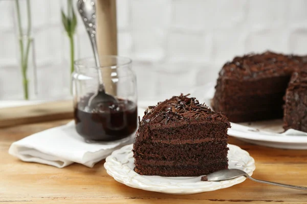 Geschnittener Schokoladenkuchen auf Holztisch, auf hellem Hintergrund — Stockfoto