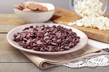 Ahşap arka plan üzerinde plaka üzerinde çikolata morsels