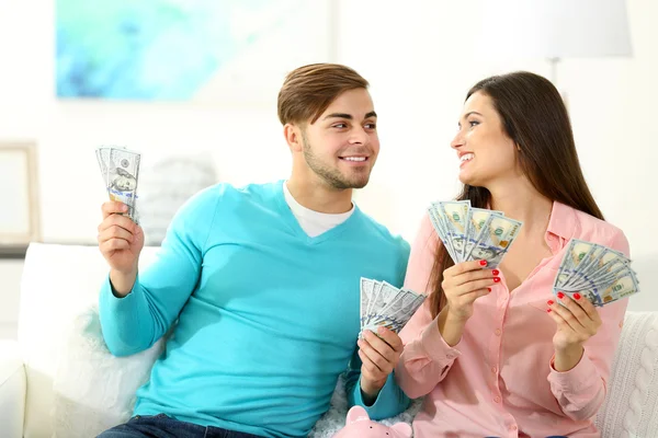 Heureux couple assis à la maison et comptant l'argent de la boîte à monnaie de porc — Photo