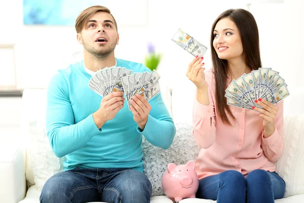 Lyckliga paret sitter hemma och räknar pengar från Sparbössa gris — Stockfoto