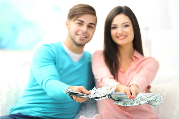 Heureux couple assis à la maison et comptant l'argent de la boîte à monnaie de porc — Photo