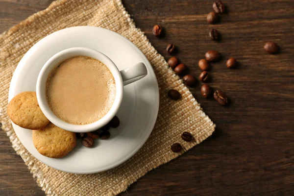 Tasse Kaffee auf Sacktuch-Serviette, auf hölzernem Tischhintergrund — Stockfoto