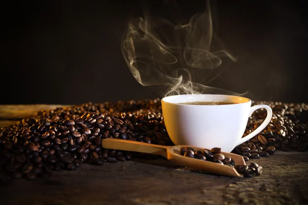 Egy csésze kávé és kávébab az asztalon. — Stock Fotó