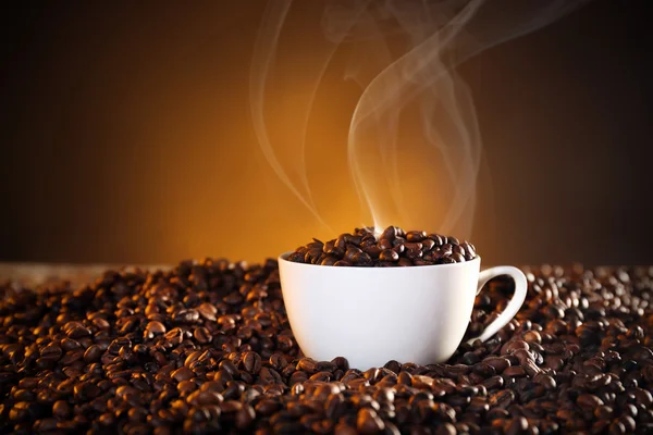 Xícara de café e grãos de café no fundo escuro — Fotografia de Stock