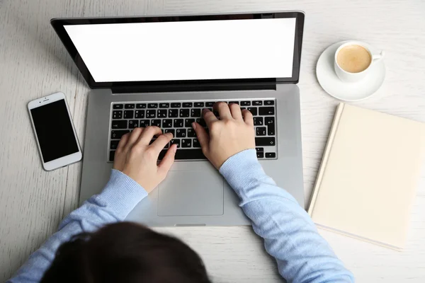 Vrouw die werkt met laptop geplaatst op houten bureau. Bovenaanzicht — Stockfoto