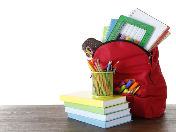 Рюкзак со школьными принадлежностями на деревянном столе на белом фоне — стоковое фото