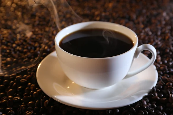 Kopje hete koffie op koffie bonen achtergrond — Stockfoto