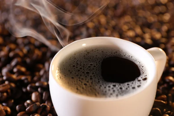 Taza de café caliente sobre fondo de granos de café — Foto de Stock