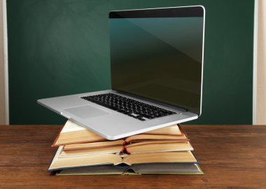 Dizüstü bilgisayar ile kitap yığını