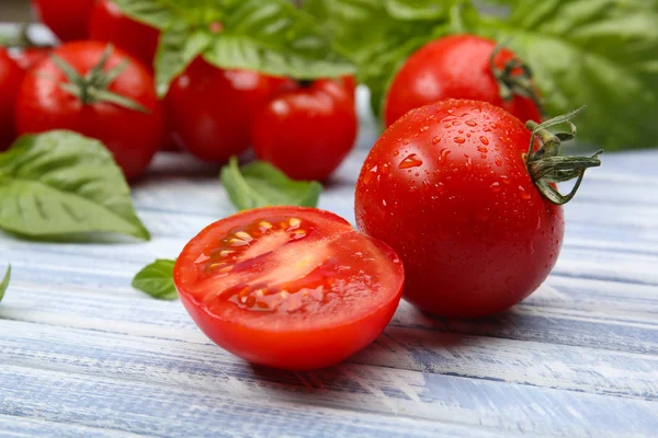 Fresh tomatoes with basil on wooden table close up — Stock Photo, Image