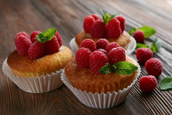 Вкусные кексы с ягодами и свежей мятой на деревянном столе вблизи — стоковое фото
