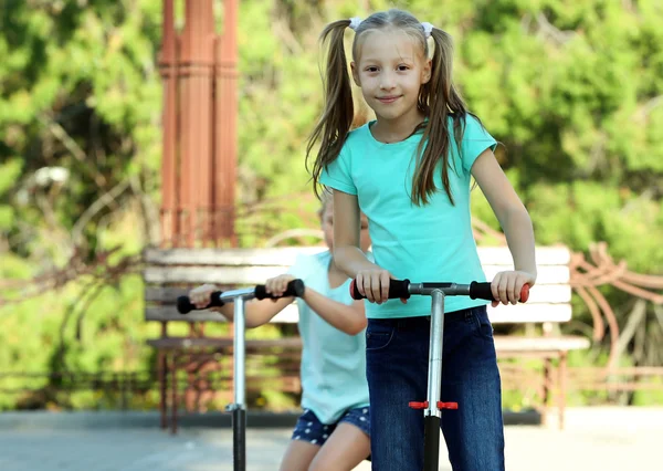 Meninas pequenas montando em scooters — Fotografia de Stock