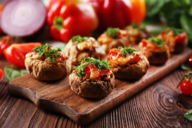 Ahşap bir tablet ile masaya sebze ve mantar dolması