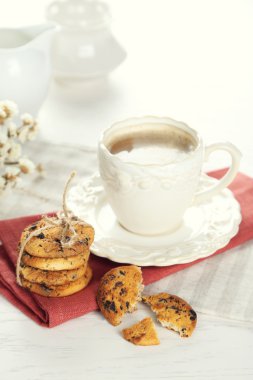 Fincan kahve ve çikolata kırıntıları Beyaz ahşap masa üzerinde lezzetli Kurabiye yığını