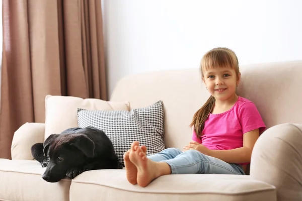 Bambina con cucciolo sul divano — Foto Stock