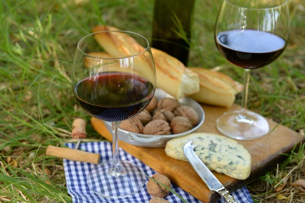 ピクニック コンセプト - ワイン、おいしいチーズ、クルミ、木の板、屋外のバゲット — ストック写真