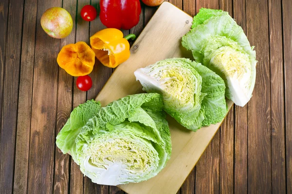 Cut savoy cabbage and pepper on wooden cutting board closeup — Stock Photo, Image