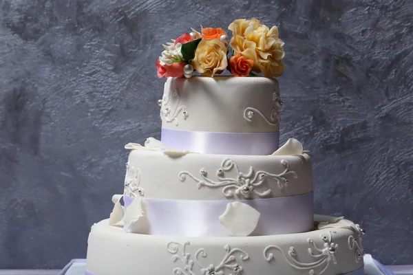Wedding cake decorated with flowers on grey background