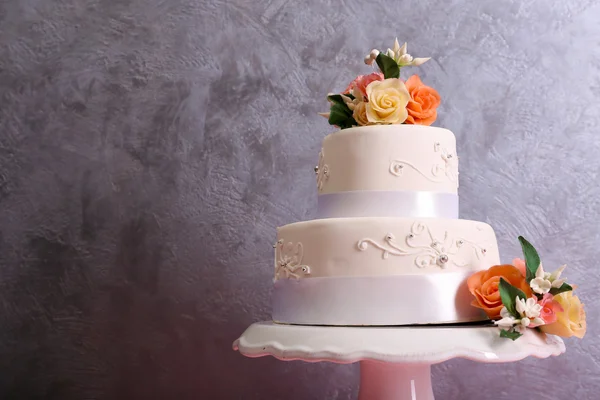White wedding cake decorated with flowers on grey background