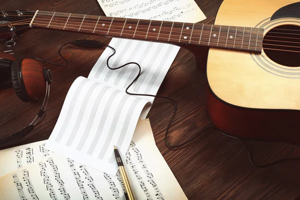 Kytaru a hudební listy na dřevěné pozadí — Stock fotografie