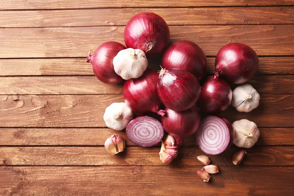 Cebollas rojas frescas con ajo sobre fondo de madera — Foto de Stock