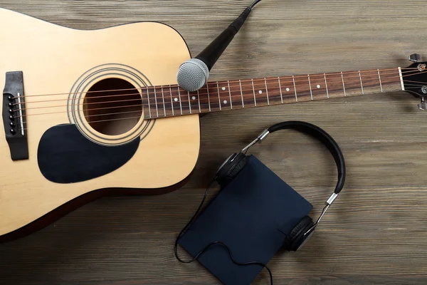 Akustická kytara, sluchátka, Poznámkový blok a mikrofon na dřevěné pozadí — Stock fotografie