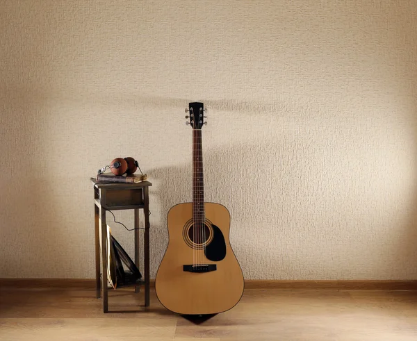 Guitarra acústica apoyada en la pared con taburete y auriculares en la habitación — Foto de Stock