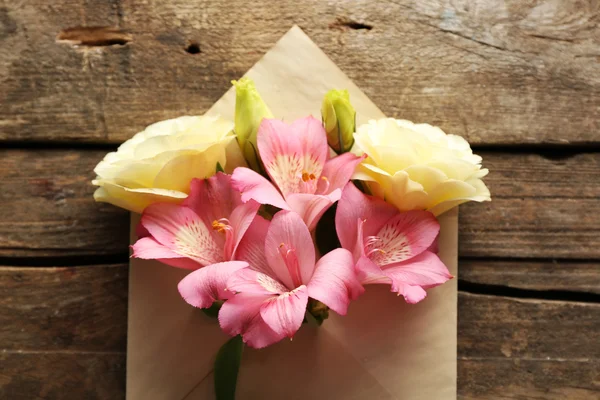 White eustoma and pink alstroemeria in envelope on wooden background — Stock Photo, Image