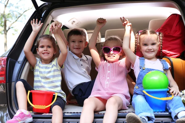 Meisjes en jongen zitten op de auto kofferbak — Stockfoto