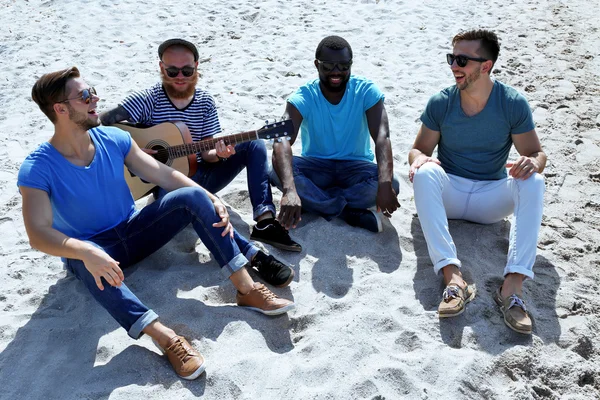 Muži, sedící na písku — Stock fotografie