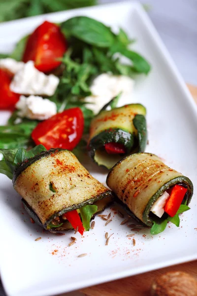 Zucchini rolls with cheese, bell peppers and arugula on plate, close-up — Stock Photo, Image