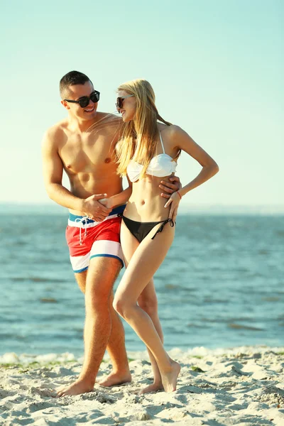 Счастливая пара обнимается на пляже — стоковое фото