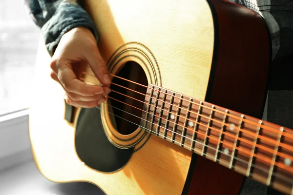 Крупним планом вид на музиканта, який грає на гітарі біля вікна — стокове фото