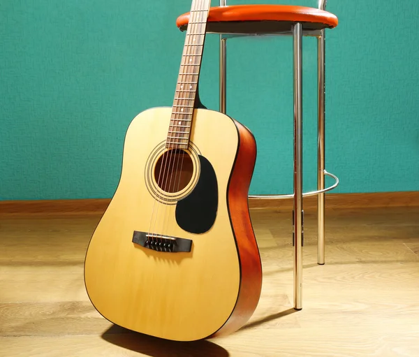 Guitare avec tabouret de bar sur le sol sur fond bleu en studio, gros plan — Photo