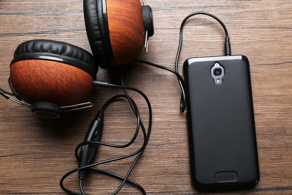Ακουστικά και smartphone για καφέ φόντο ξύλινη — Φωτογραφία Αρχείου