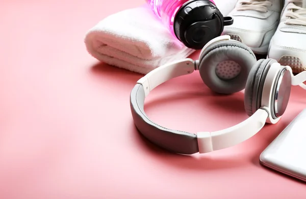 Słuchawki, sprzęt sportowy na różowym tle — Zdjęcie stockowe