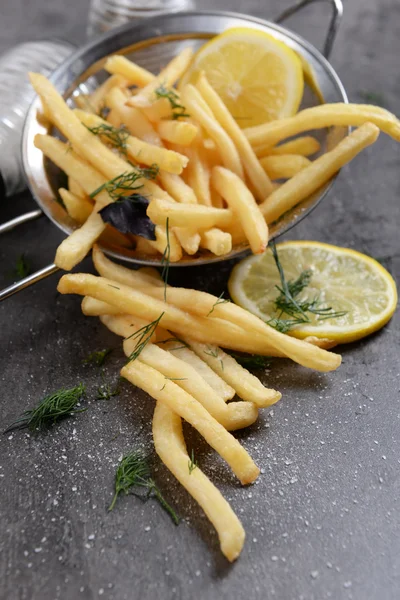 French fries with lemon and salt in sieve on table — Stock Photo, Image