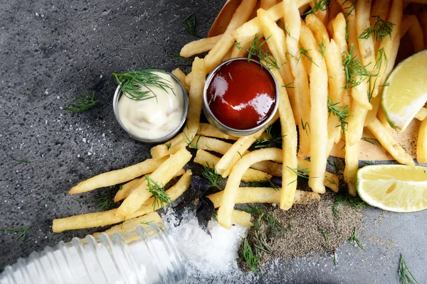 Franse frietjes in zak met saus, limoen en kruid op tafel — Stockfoto