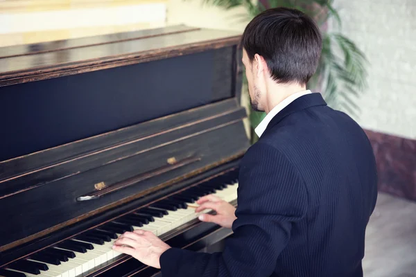 Homem de terno preto toca piano — Fotografia de Stock